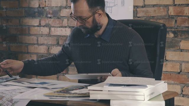 A Stylish Business Man Is Sitting At A Table Using A Tablet