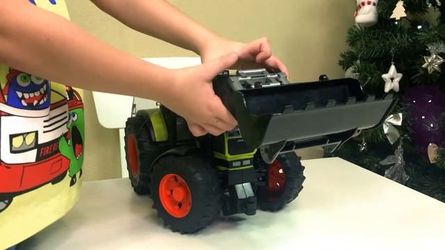 Мальчик играет с трактором на больших колесах.