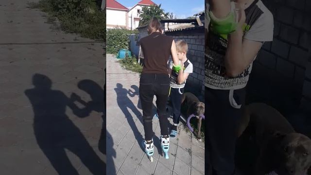 Младший брат учит старшую сестру кататься на роликах
