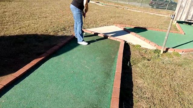 Бабушка играет в мини гольф в яблочном саду.