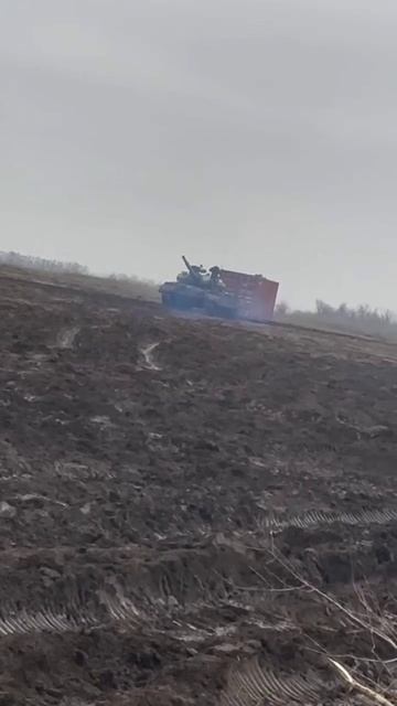 Танк Т-62 Вооруженных сил Российской Федерации буксирует транспортный контейнер по полю