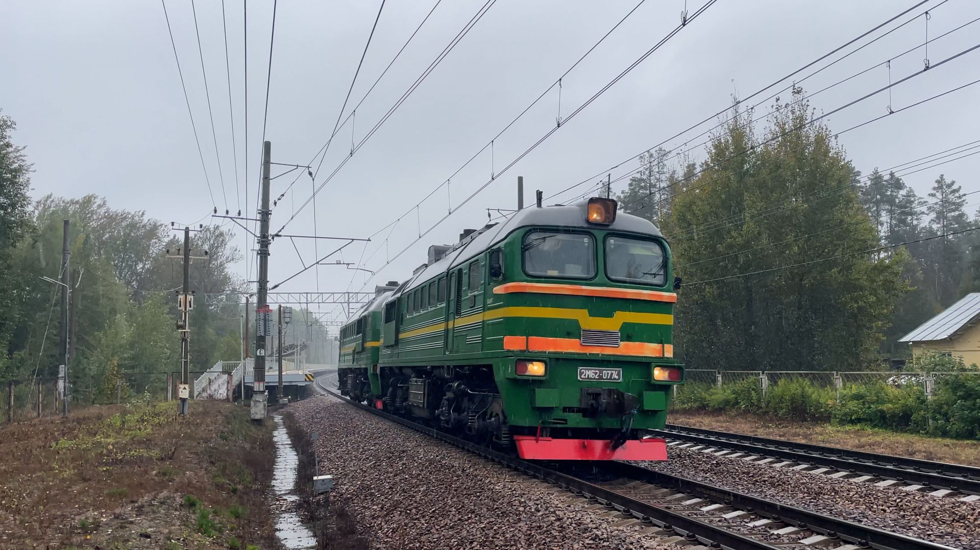 Зелёный тепловоз 2М62 едет в сильный дождь