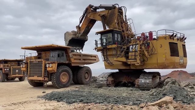 Огромный карьерный экскаватор Caterpillar 6040 Загружает самосвалы Hitachi EH3500