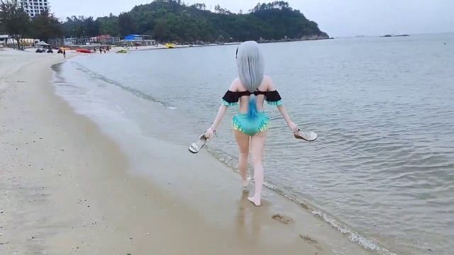 Кигуруми-кукла в купальнике идет по кромке прибоя.