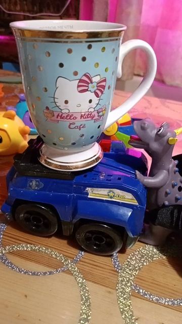 Динозавр везет кружку хелоу Китти. Она катается на машине щенячий патруль.