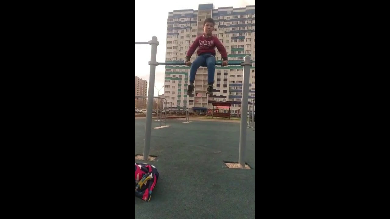 мальчик крутится на перекладине