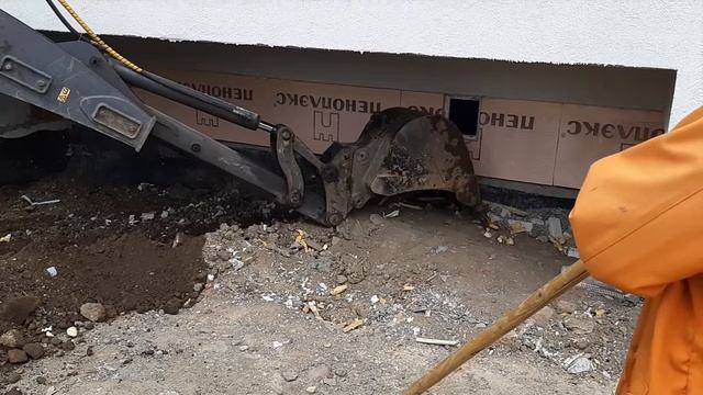 Видео экскаватор-погрузчик Volvo выбирает грунт для отмостки дома