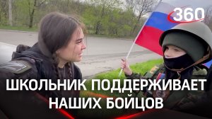 Мальчик с российским флагом стоит у дороги, чтобы поддержать наших бойцов
