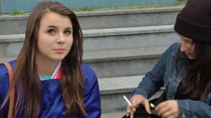 2 girls smoking at a building