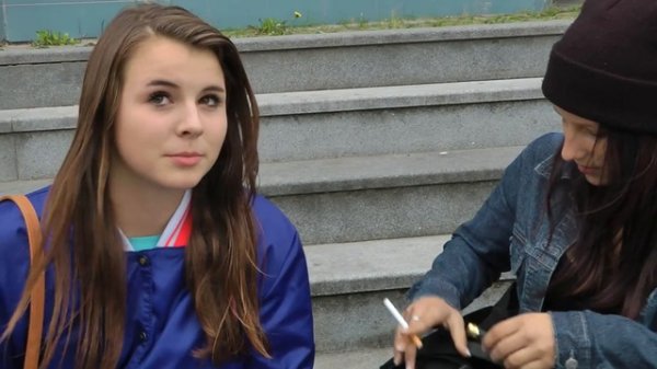 2 girls smoking at a building