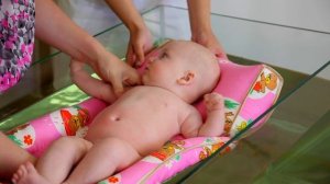 Купание новорожденного малыша на плотике для новорожденных