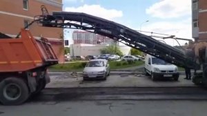 Дорожные работы. Дорожная фреза срезает верхний старый слой асфальта и засыпает в оранжевый самосва