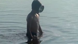 Мальчик пытается нырять в речку в маске