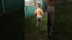 Мальчик косит траву триммером