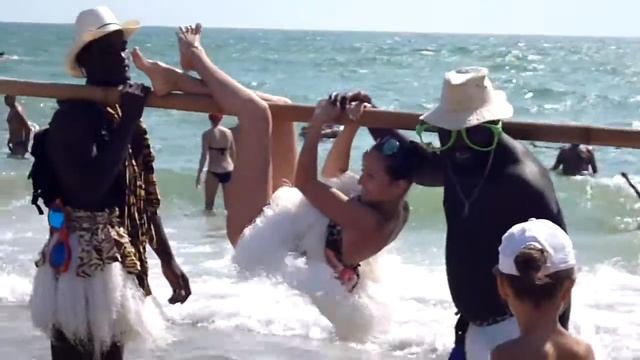 негры на пляже держат девушку на палке