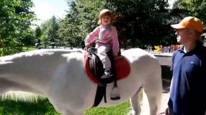 Верхом на лошадке. Дети катаются на лошади в парке.