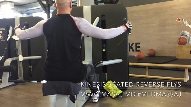 Махи руками назад сидя на тренажёре Kinesis