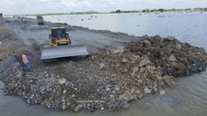 Строительство насыпной дороги на воде. Бульдозер разравнивает грунт, который привозят самосвалы