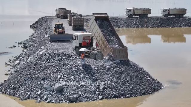 Строительство насыпной дороги. Подвоз камней и грунта самосвалами, разравнивание их бульдозером смотреть онлайн