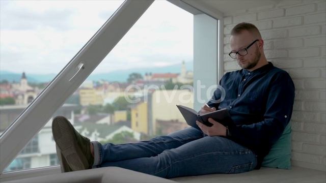 Young Man Is Sitting Near the Window Writes in a Notebook | Stock Footage - Videohive смотреть онлайн