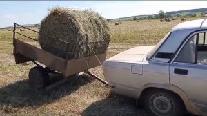 Погрузка рулона сена в прицеп легкового автомобиля