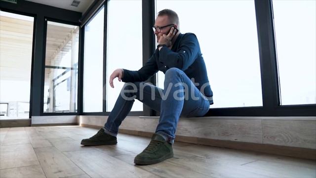 Young Sad Man Is Sitting Near Panoramic Window and Speaking on the Phone | Stock Footage - Videohiv смотреть онлайн