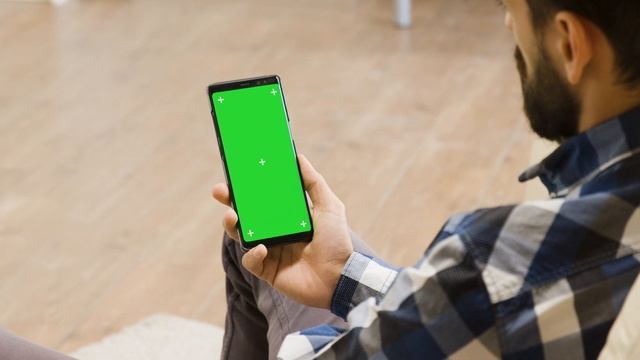 young man on the couch looking at green screen phone zoom in parallax footage Green Screen смотреть онлайн