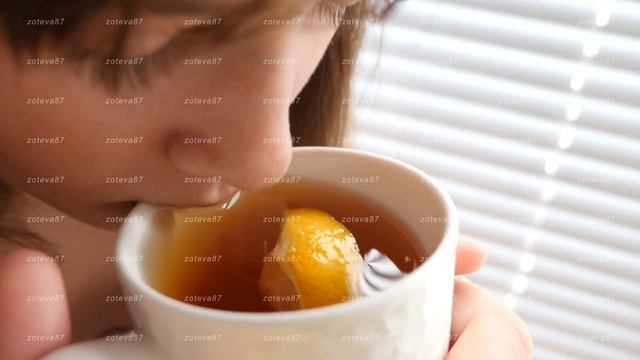 Beautiful girl drinks from mug hot tea with lemon looking out window. смотреть онлайн
