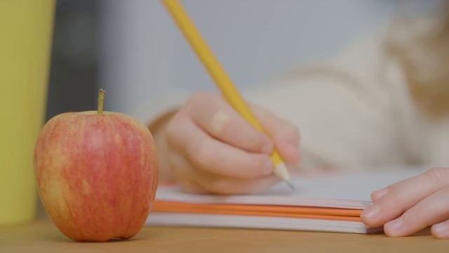 Close Up Of Child Writing In Book At Table With Apple In Foreground смотреть онлайн