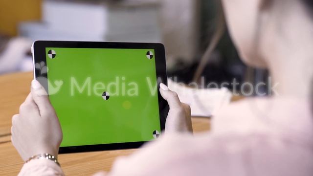 Rear view of a brunette woman using tablet with green screen, modern technologies concept. Stock смотреть онлайн