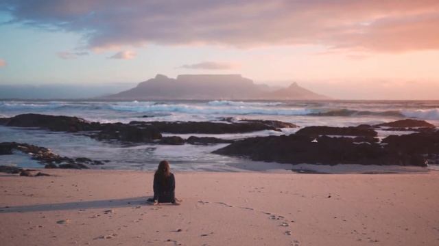 A woman seated on the beach sand enjoying the table mountain view смотреть онлайн