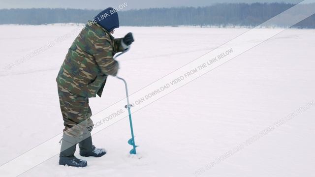 Winter Fishing On River. A Man Drills A Hole In Ice
