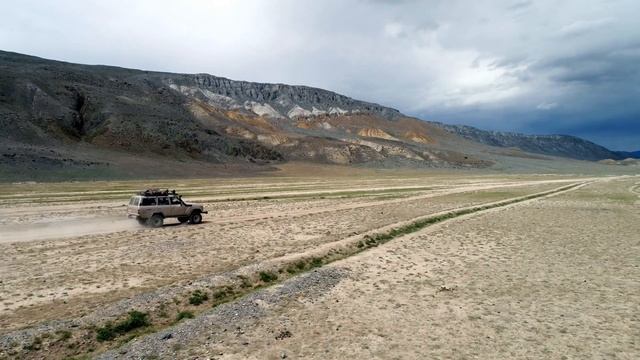 aerial view of safari vehicle driving on sand track road in the altay mountain смотреть онлайн
