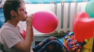 Симпатичная девушка надувает шары-сердечки