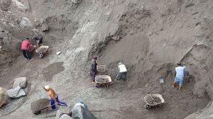 Строительство, трое шахтёров сбрасывают песок с разных сторон