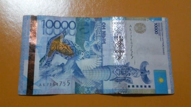 БАНКНОТА 10 000 ТЕНГЕ № серии АК7364755 на светло-коричневой поверхности 1-го Марта - ДЕНЕЖНЫЙ ПОТО смотреть онлайн