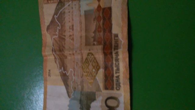 БАНКНОТА ТЫСЯЧА ТЕНГЕ обратной стороной на зелёной поверхности Двадцать Шестого Ноября смотреть онлайн