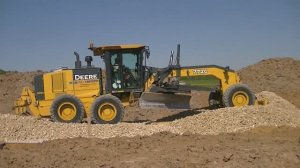 Грейдер John Deere 772G распределяет щебень