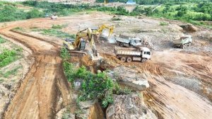 Экскаватор CAT 320 разбивает большие камни стальным шаром.