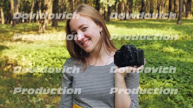 A young girl photographer with a camera poses in the park. смотреть онлайн