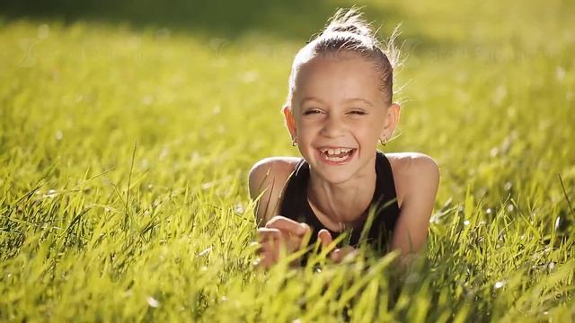 Little girl at sunset on the grass and smiling at camera смотреть онлайн
