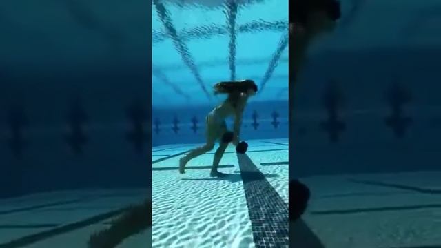 девушка с гантелями под водой в бассейне