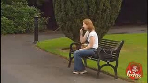 Boy peeing behind trash can outside.