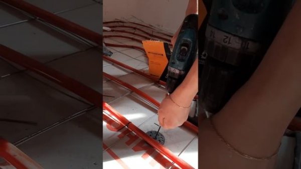 Жена учится закручивать саморезы шуруповертом.