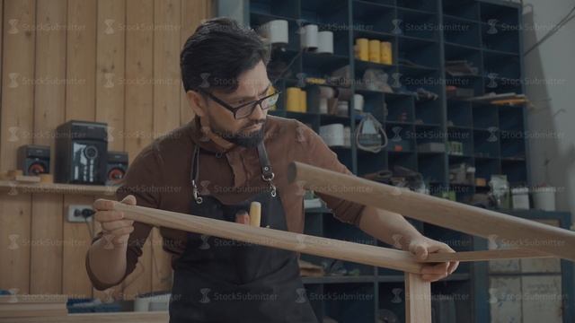 Carpenter in workshop assembles two pieces of a table смотреть онлайн