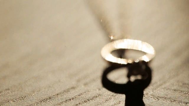 golden wedding ring hanging on a golden chain against white background top view смотреть онлайн