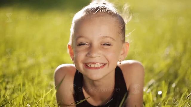 Little girl at sunset on the grass and smiling at camera смотреть онлайн