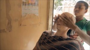 Молодой индийский уличный парикмахер — бритье и массаж головы