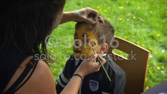 Young boy has his face painted at an English Carnival or Fete - THIS FOOTAGE IS FOR SALE. смотреть онлайн
