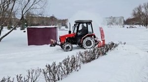 Уборка снега в городском сквере минитрактором Уралец с роторным снегоочистителем.